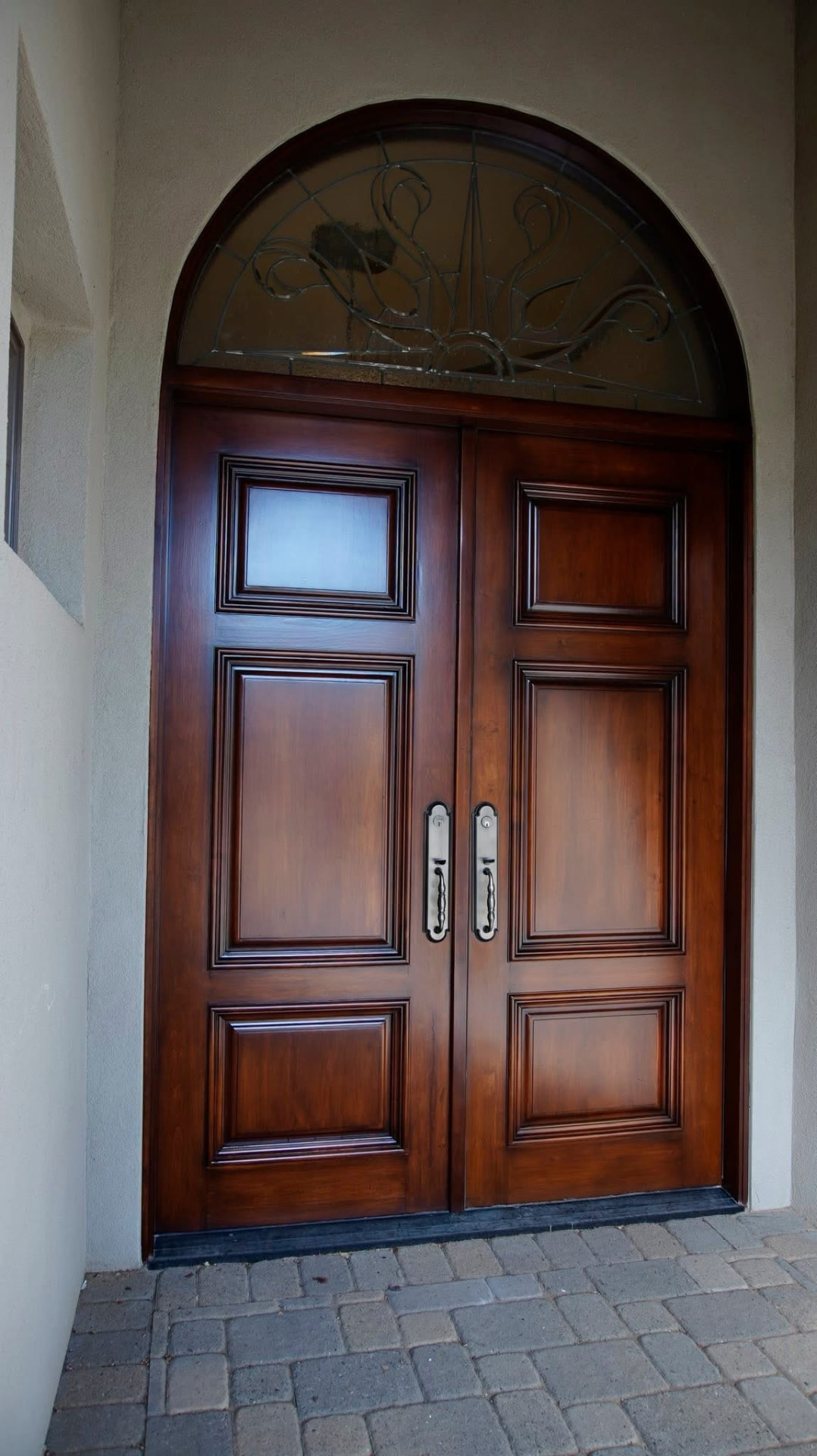 Finished arched double entry doors with a rich restored stain